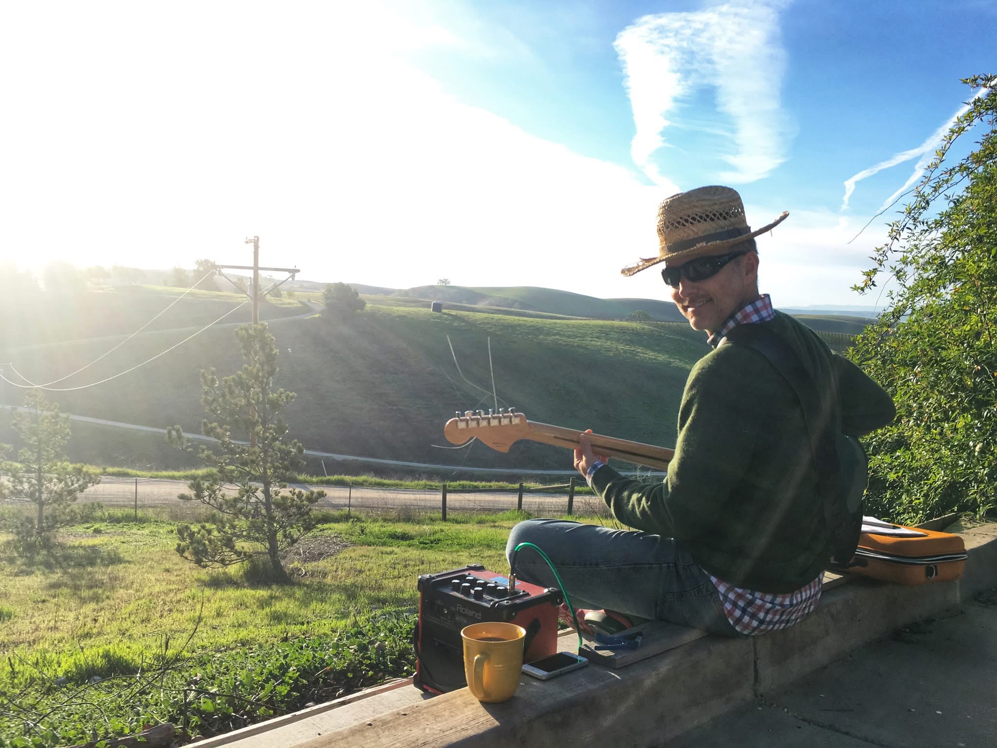 Timothy of the band Artichoke playing guitar near a field